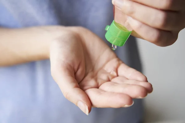 Kadın şişeden ellerine kum dezenfektanı sıkıyor.