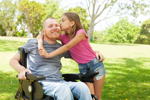 Little daughter kissing her disabled father. — Stock Photo, Image