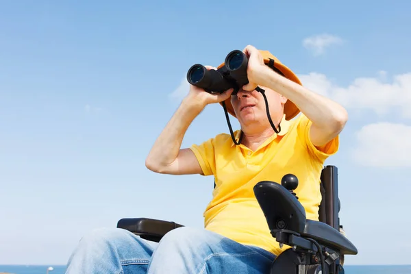 Zdravotně postižený muž s binokulární. — Stock fotografie