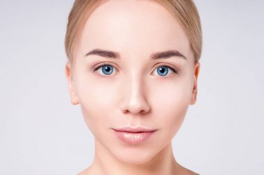 Güzel kadın portre yüz. Güzellik Portresi. Güzel Spa modeli mükemmel taze temiz ten kızla. Sarışın kadın gri arka plan kameraya bakıyor. Gençlik ve cilt bakım kavramı.