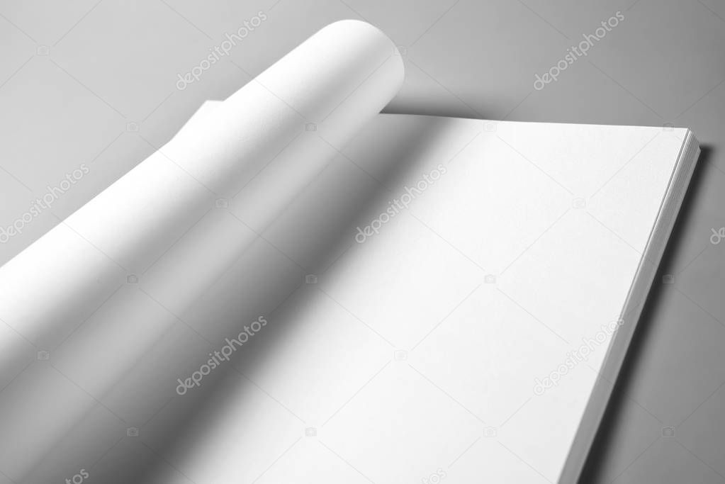 Blank sheets of paper with curled upper page over grey background