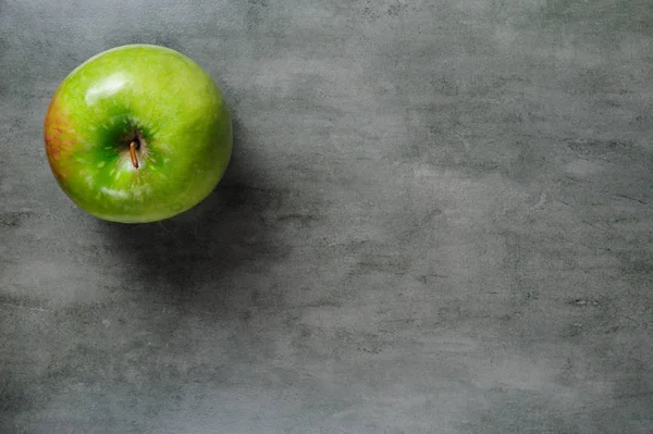 Jedno zielone jabłko na ciemnym tle kamień, widok z góry. — Zdjęcie stockowe