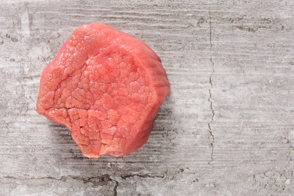 Trozo de carne de res cruda sobre piedra agrietada o fondo de hormigón —  Fotos de Stock