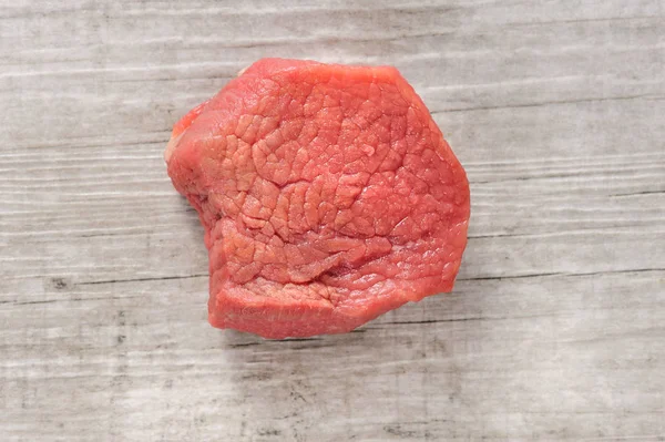 Kawałek mięsa surowego mięsa wołowego na biały drewno lub kamień tło — Zdjęcie stockowe