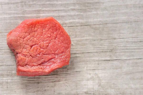 Trozo de carne de res cruda sobre fondo de madera blanca o piedra —  Fotos de Stock
