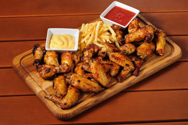 Big wooden board with grilled chicken winds — Stock Photo, Image