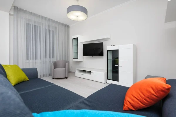 White living room with TV set, chair and grey sofa