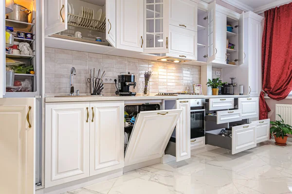 Luxusní moderní bílý kuchyňský interiér s otevřenými dveřmi a zásuvkami — Stock fotografie