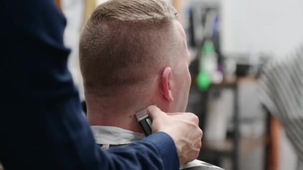 Mens haircut in Barbershop. Close-up of master clipping a man with blond hair with clipper — Stock Video