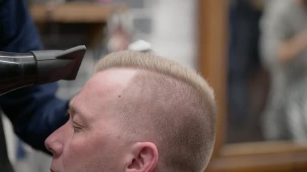 Mens haircut in Barbershop. Close-up of master clipping a man with blond hair with scissors — Stockvideo