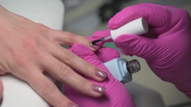 Closeup of manicure beautician covering clients nails with clear protection on glitter nail polish — Stock video