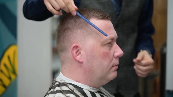 Corte de pelo para hombre en la barbería. Primer plano del maestro cortando a un hombre con el pelo rubio con la cortadora — Vídeos de Stock