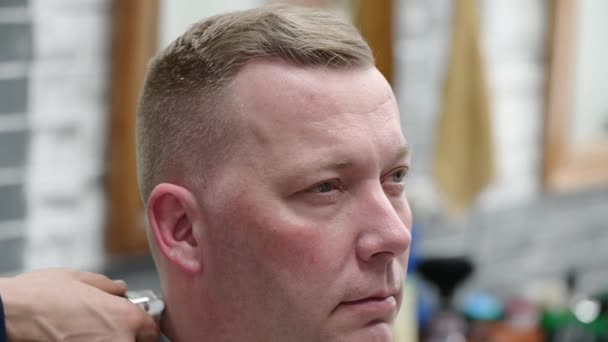 Mens haircut in Barbershop. Close-up of master clipping a man with blond hair with clipper — Stock video