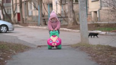 Oyuncak araba süren iki yaşında küçük bir kız.