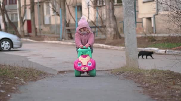 Niña de dos años montando un coche de juguete — Vídeos de Stock