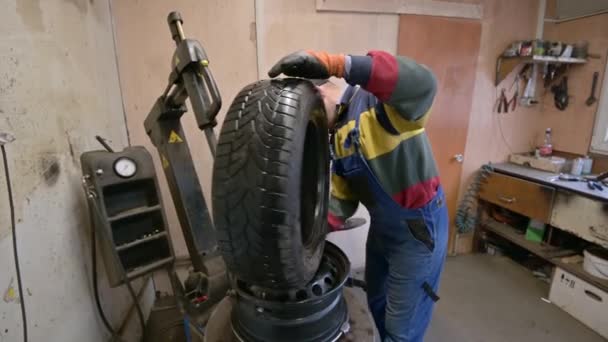 Trabajador técnico cabe neumático en la rueda en el garaje — Vídeos de Stock