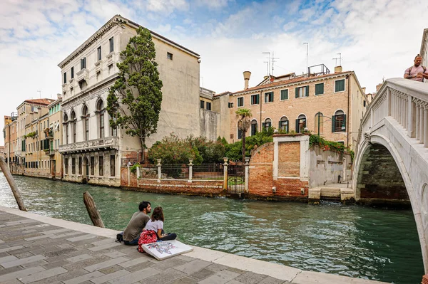 Venecia, Italia. Pareja románica sentada en la acera de los canales cerca del puente en la parte histórica de la ciudad — Foto de Stock
