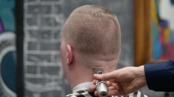 Corte de cabelo dos homens na Barbearia. Close-up de mestre cortando um homem com cabelo loiro com clipper — Vídeo de Stock