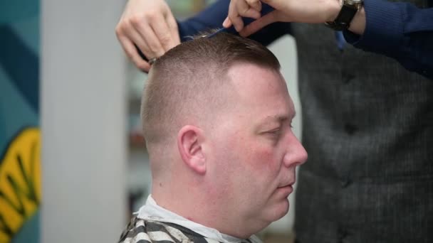 Herrenfrisur im Barbershop. Nahaufnahme des Meisters, der einem Mann mit einem Haarschneider die Haare schneidet — Stockvideo