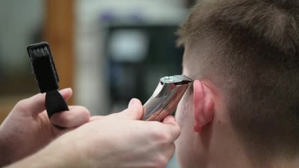 Joven hombre corte de pelo en la barbería. Primer plano del cabello de recorte maestro con clipper — Vídeos de Stock