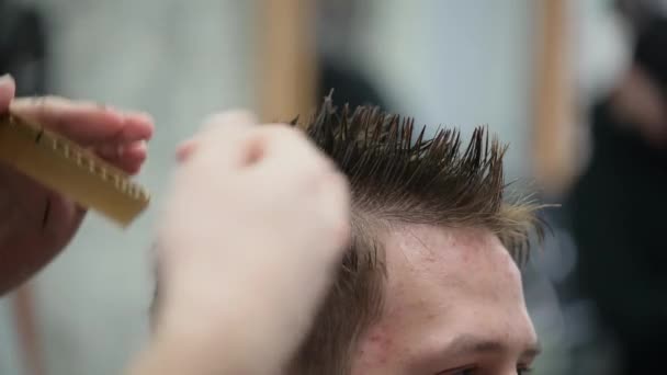 Young mans haircut in Barbershop. Close-up of master clipping hair with scissors and comb — Stock Video
