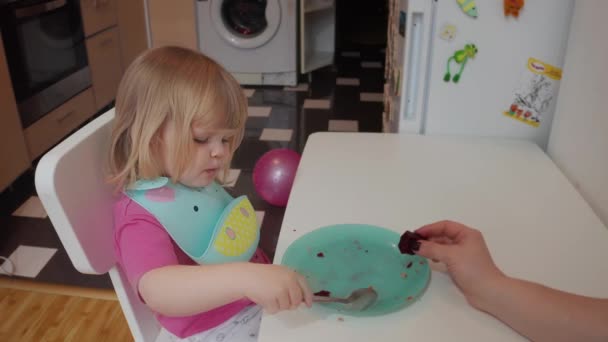 Klein twee jaar oud blond blauw-eyed meisje met haar eten, 4k schot — Stockvideo
