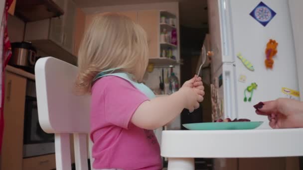 Piccolo due anni bionda dagli occhi azzurri ragazza avendo il suo pranzo, 4K shot — Video Stock