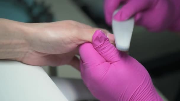 Manicura esteticista prepara las uñas de los clientes con una lima de uñas antes de cubrirlo con esmalte, primer plano — Vídeos de Stock