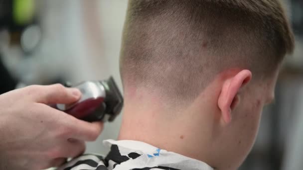 Taglio di capelli del giovane in barbiere. Primo piano di master clipping capelli con clipper nella parte posteriore della testa — Video Stock