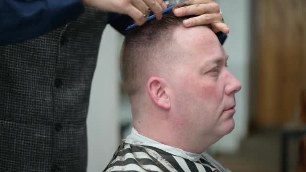 Corte de cabelo dos homens na Barbearia. Close-up de mestre cortando um homem com cabelo loiro com clipper — Vídeo de Stock
