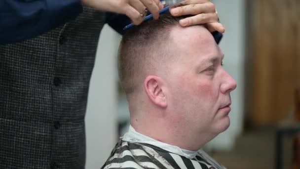 Corte de pelo para hombre en la barbería. Primer plano del maestro cortando a un hombre con el pelo rubio con la cortadora — Vídeos de Stock