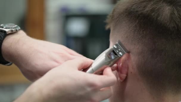 Fiatal férfiak hajvágása a fodrászatban. Közelkép a mester nyírás haj vágó ollóval — Stock videók