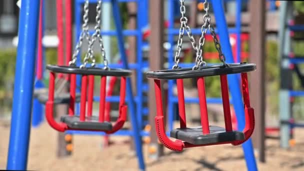 Schaukeln in Zeitlupe auf leerem Kinderspielplatz in Wohngebiet — Stockvideo