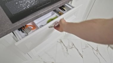 Erkek eli mutfak çekmecesine bir şeyler koyar.