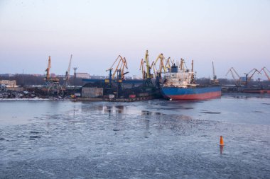 Nakliye konteyner yük ve gaz petrol tankları rıhtımda. ithalat ihracat ve lojistik iş. Kargo gemisi, limana demirledi. Kargo Vinçler kış akşam bağlantı noktası Riga, Letonya.