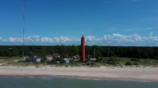 空中ドローンショットAkmenragsバルト海のラトビア沿岸の灯台は パヴィオスタのリゾートタウンの南に位置しています 晴れた夏の日 現在の塔は1921年に建てられた — ストック動画