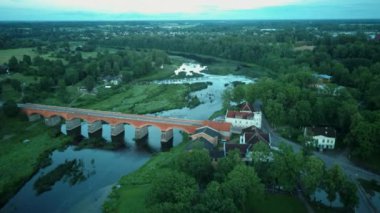 Letonya Kuldiga 'da Avrupa' nın en geniş şelalesinin üzerinde uçmak ve Venta Nehri 'nin karşısındaki tuğla köprü üzerinde güneş doğduktan sonraki akşam uçmak. Areal Dron Vuruşu.