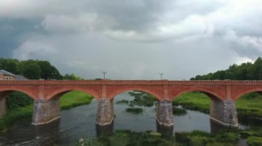Letonya Kuldiga 'da Avrupa' nın en geniş şelalesinin üzerinde uçmak ve Venta Nehri 'nin karşısındaki tuğla köprüsünde güneş battıktan sonraki sabah. Areal Dron Vuruşu.