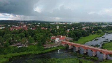 Letonya Kuldiga 'da Avrupa' nın en geniş şelalesinin üzerinde uçmak ve Venta Nehri 'nin karşısındaki tuğla köprüsünde güneş battıktan sonraki sabah. Areal Dron Vuruşu.