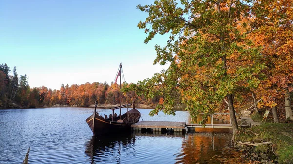 The Tourist Boat in the Style of a Viking Ship on the River Perse. Autumn Old Koknese Castle Ruins. Perse is a Tributary to Daugava River in Latvia.