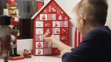 Mutlu küçük çocuk, arka planda Noel fındıkkıranı olan takvim evi formundan tatlı aldı. Çocuklar için Geleneksel Noel Takvimi