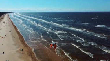 Kiteboardcuların ve Kitesurfers 'ın Baltık Denizi' ndeki Letonya Hava Aracı 4k 'de çekilmiş görüntüleri. Güneşli bir bahar günü. Uçurtma Tahtasında Uçan Adam