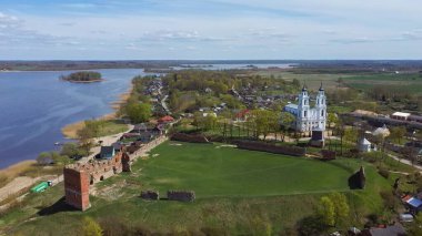 Ludza Ortaçağ Kalesi 'nin Büyük Ludza Gölü ile Küçük Ludza Gölü arasındaki bir tepedeki havadan görünüşü ve Arka plandaki Roma Katolik Kilisesi
