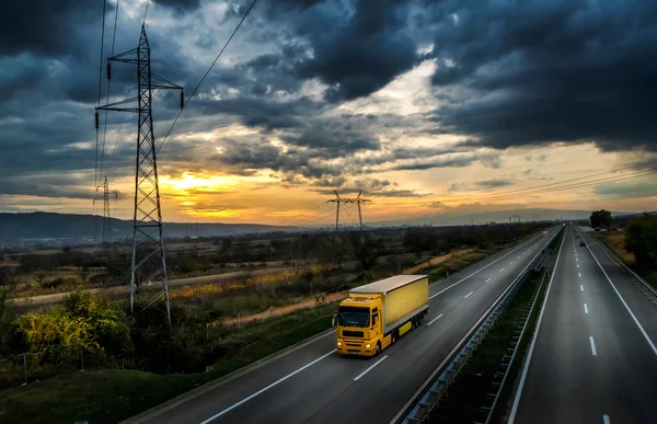 Yellow lorry on a highway at sunset — Stock fotografie