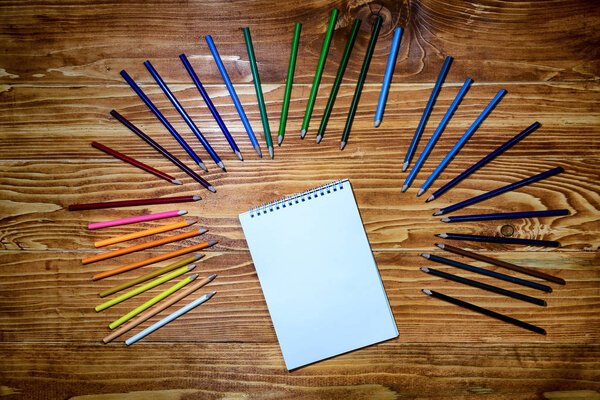 Empty notebook with color pencils on the wooden table