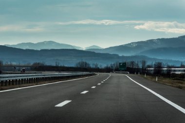 İki satır geniş karayolu kırsal manzara dağlara giden bir bulutlu kış gününde