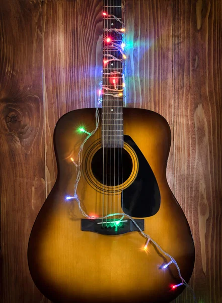 Ahşap duvar arka plan üzerinde Noel ışıkları ile gitar