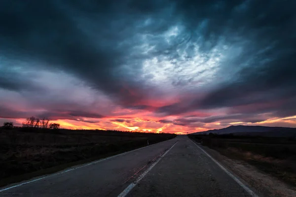 Düz Otoban yol dramatik bir ateşli Sunset yakınında alacakaranlık