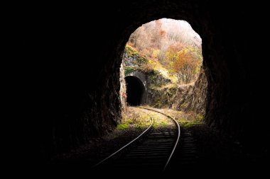 Resimli kırsal manzarada kısa tünellerden geçen eski terk edilmiş demiryolu.