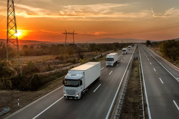 Konvoi Blauer Lastkraftwagen Auf Einer Landstraße Unter Herrlich Orangefarbenem Sonnenuntergang — Stockfoto